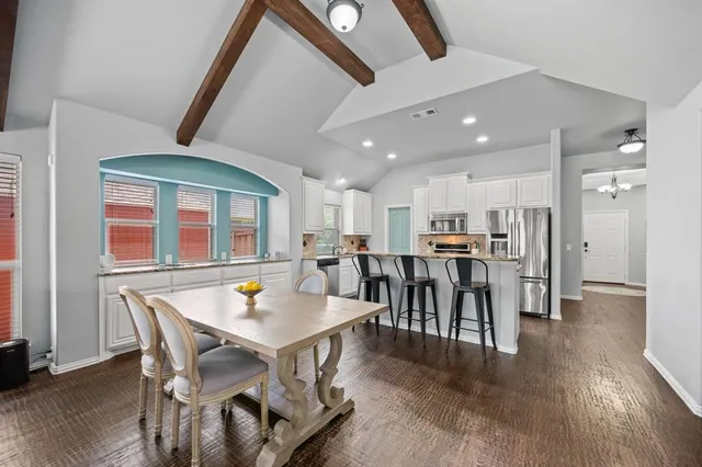 a open dining room with stainless steel appliances kitchen island granite countertop a dining table chairs and a kitchen view