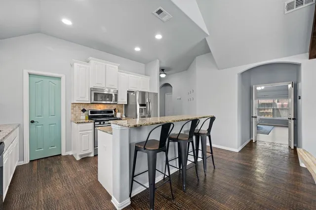 a kitchen with stainless steel appliances a table chairs refrigerator and microwave