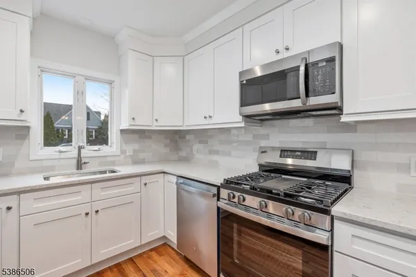a kitchen with stainless steel appliances granite countertop grey cabinets a stove a sink and dishwasher
