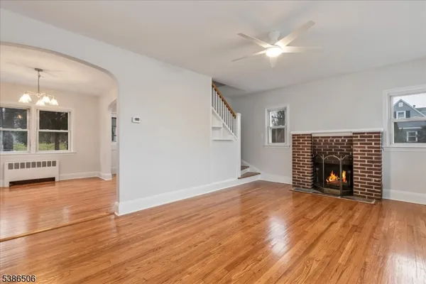 an empty room with wooden floor fireplace and windows