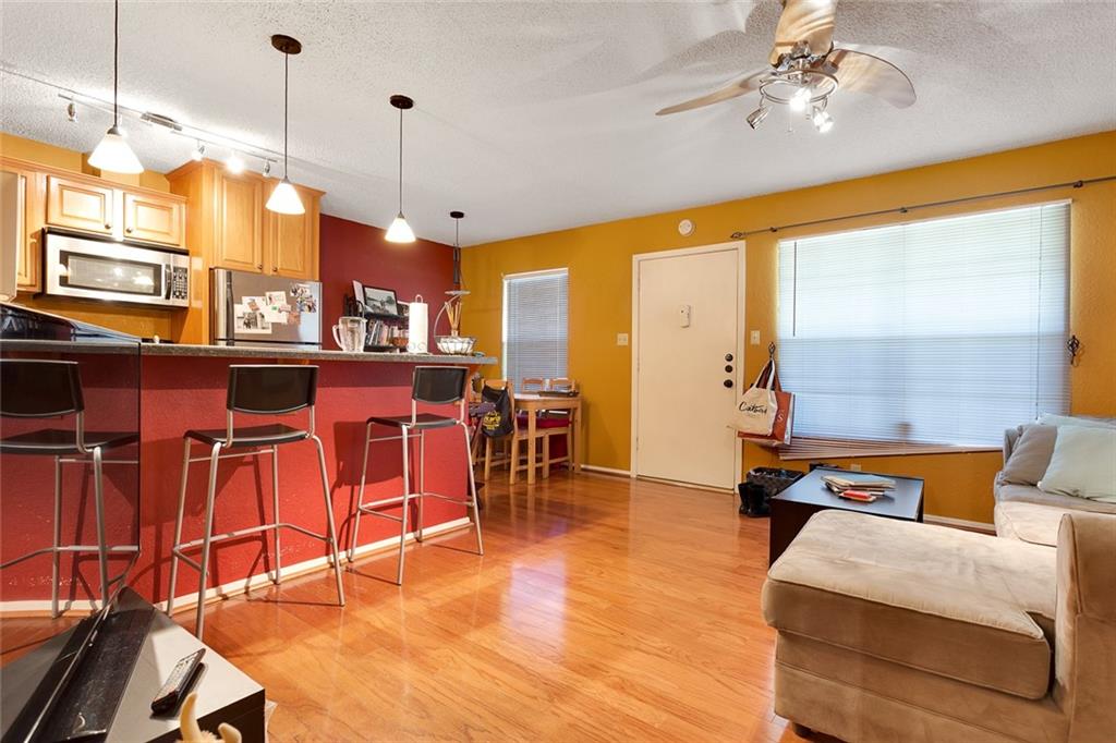 910 Duncan Lane, Unit 35 Austin, TX 78705 - Photo 2 of 20 A well-lit living area features warm wood flooring and a functional kitchen island for casual dining.