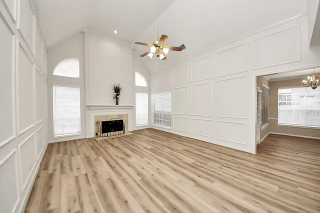 a view of empty room with wooden floor and fan