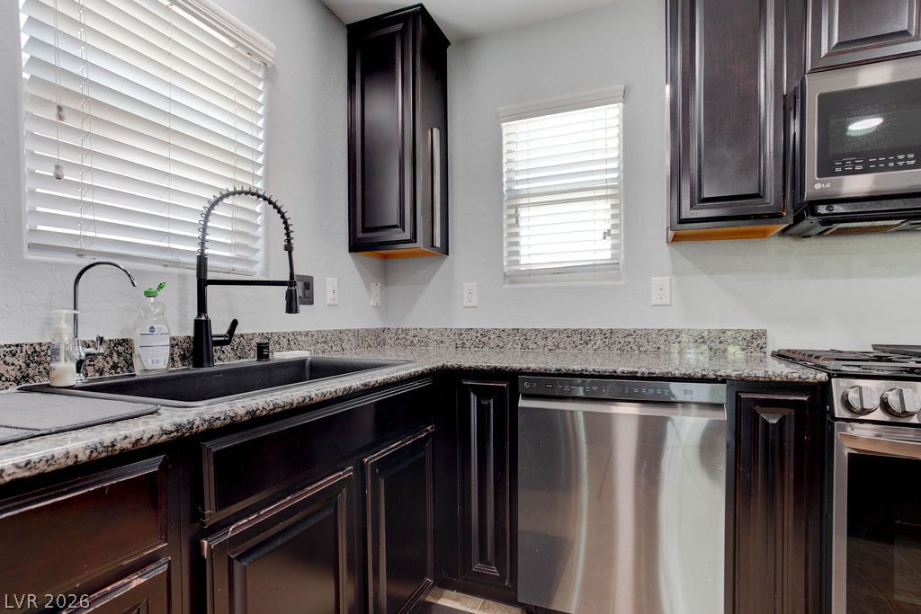 7724 Vibrant Thread Court Las Vegas, NV 89149 - Photo 9 of 43 Granite counters and dark cabinetry define this functional and well-equipped kitchen space.