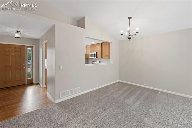 6725 Akron Road Colorado Springs, CO 80923 - Photo 16 of 50 Carpeted foyer featuring an inviting chandelier and lofted ceiling