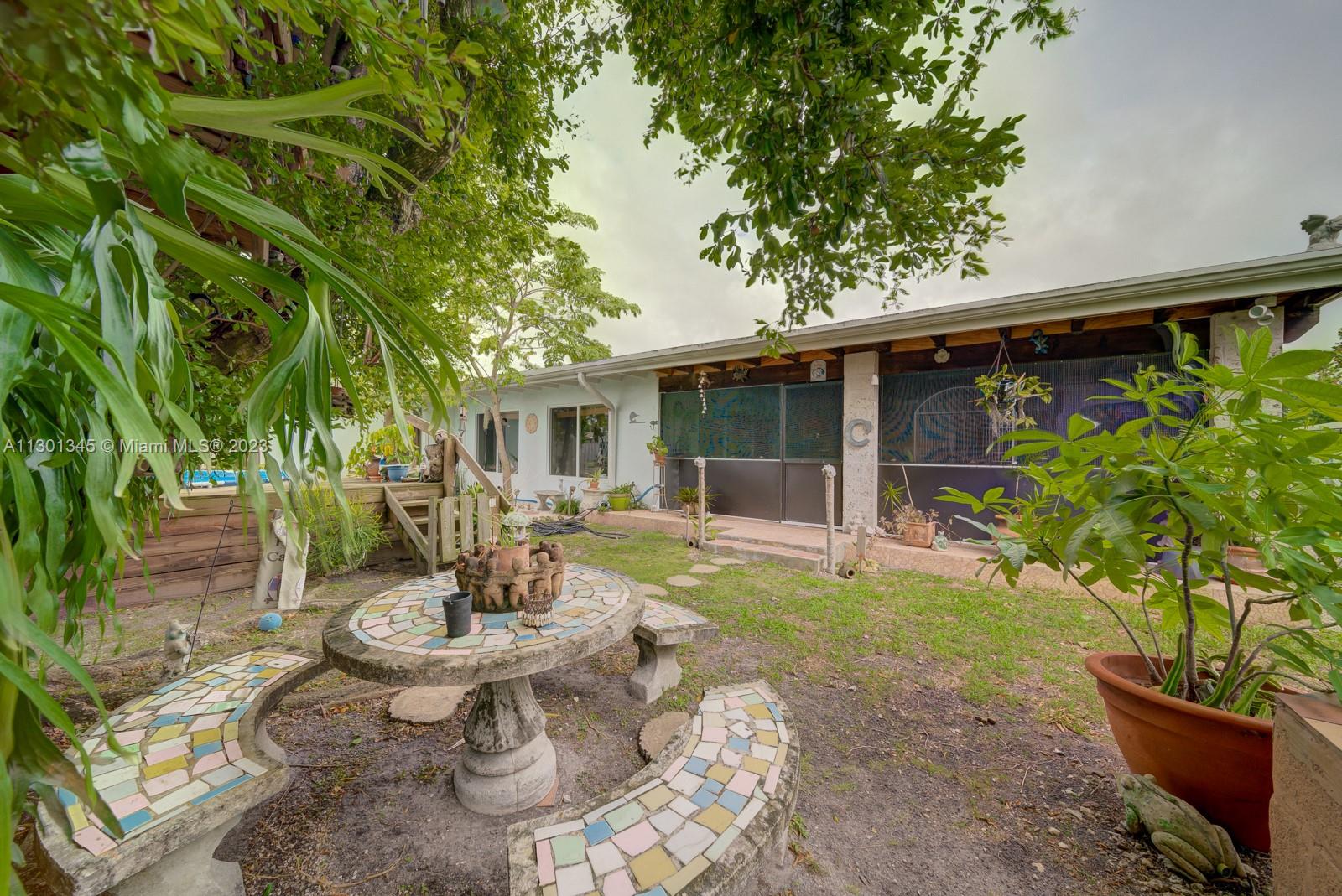 9520 April Road Cutler Bay, FL 33157 - Photo 8 of 26 a view of a patio with table and chairs potted plants and large tree