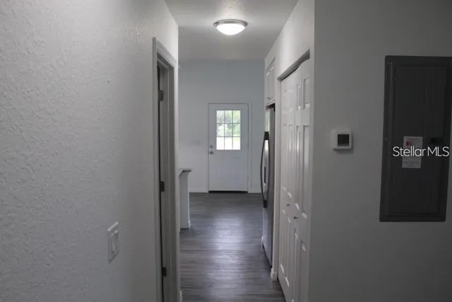 a view of a hallway with wooden floor and a bathroom