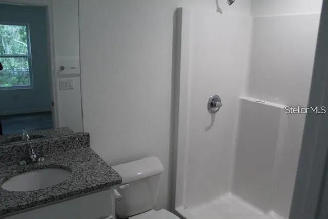 a bathroom with a granite countertop sink a toilet and shower