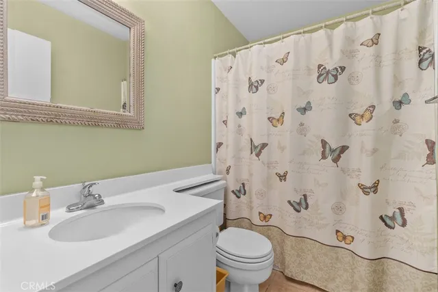 a bathroom with a granite countertop sink toilet and mirror