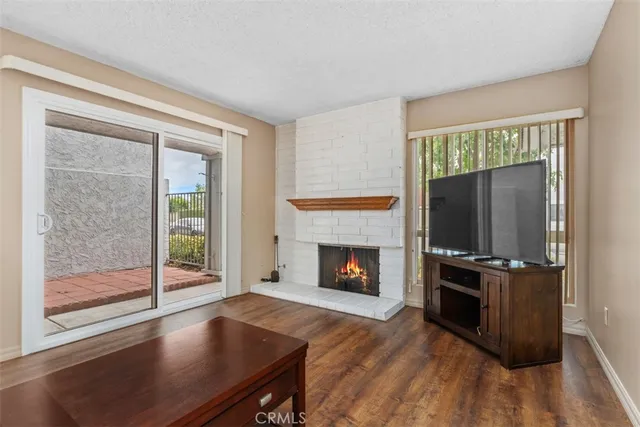 an empty room with wooden floor fireplace and windows