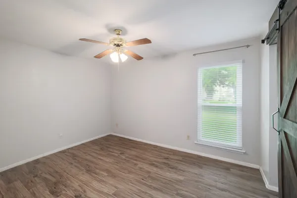 a view of a livingroom with a fireplace a chandelier a wooden floor and a ceiling fan
