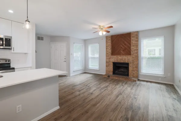 an empty room with wooden floor fireplace and windows