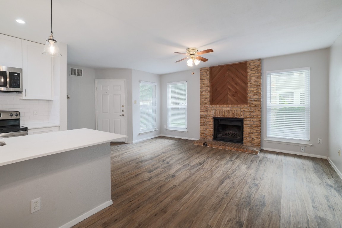 10616 Mellow Meadow Drive, Unit 46A Austin, TX 78750 - Photo 4 of 23 Standing in the dining area, looking into the living room with floor to ceiling fireplace, large windows, and the front door to the left of the fireplace.