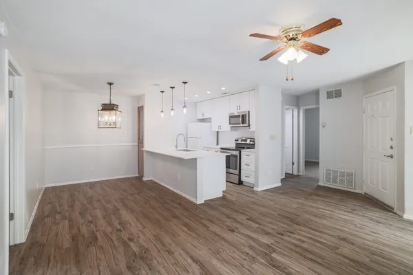 a view of a livingroom with a fireplace a ceiling fan and wooden floor