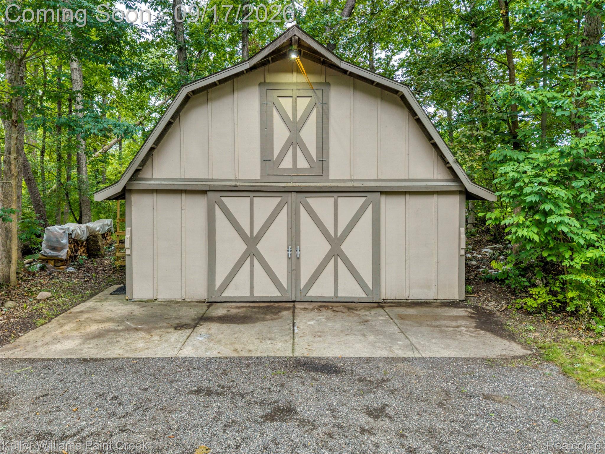4535 Orion Road Rochester, MI 48306 - Photo 13 of 67 Gambrel roof barn with sliding double doors, a concrete pad, and an upper gable window