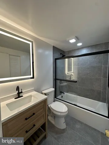 a bathroom with a bathtub shower sink vanity mirror and toilet