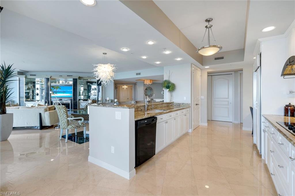 700 La Peninsula Boulevard, Unit 305 Naples, FL 34113 - Photo 11 of 39 a large kitchen with kitchen island a large counter top space a sink stainless steel appliances and cabinets