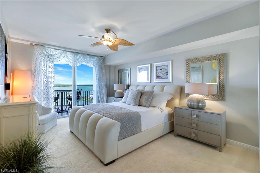700 La Peninsula Boulevard, Unit 305 Naples, FL 34113 - Photo 20 of 39 a bedroom with a large bed and a chandelier fan