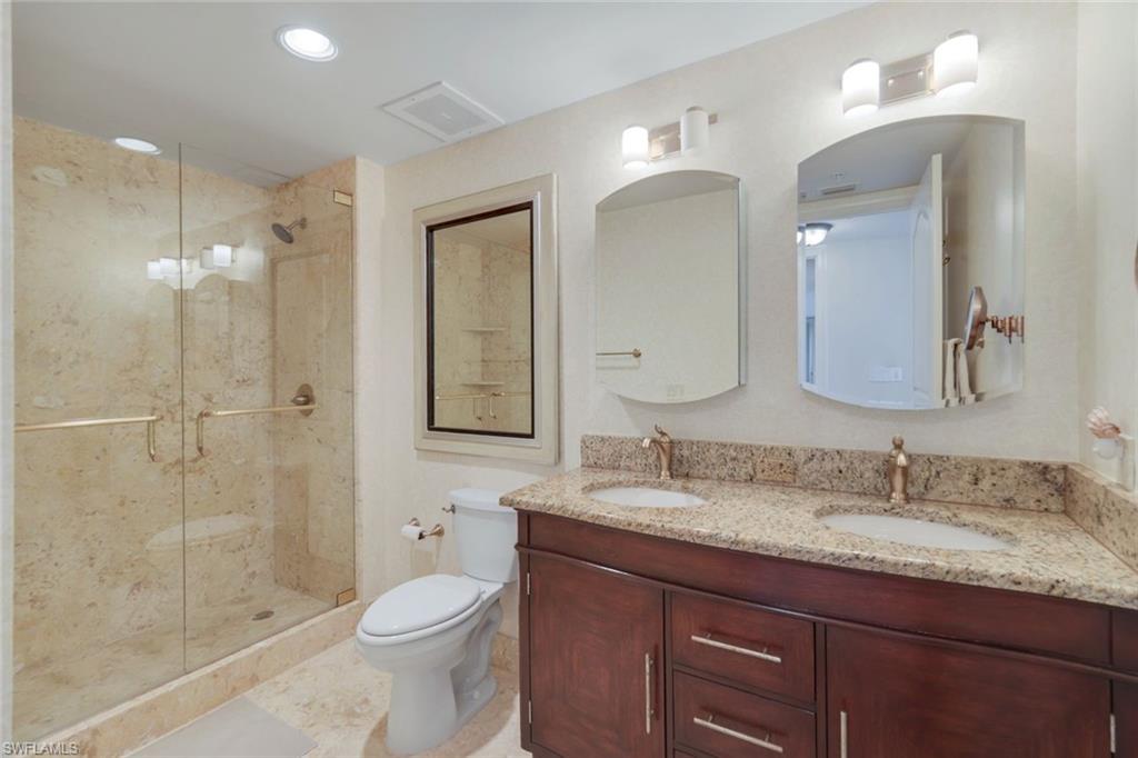 700 La Peninsula Boulevard, Unit 305 Naples, FL 34113 - Photo 25 of 39 a bathroom with a granite countertop sink toilet a large mirror a shower and vanity