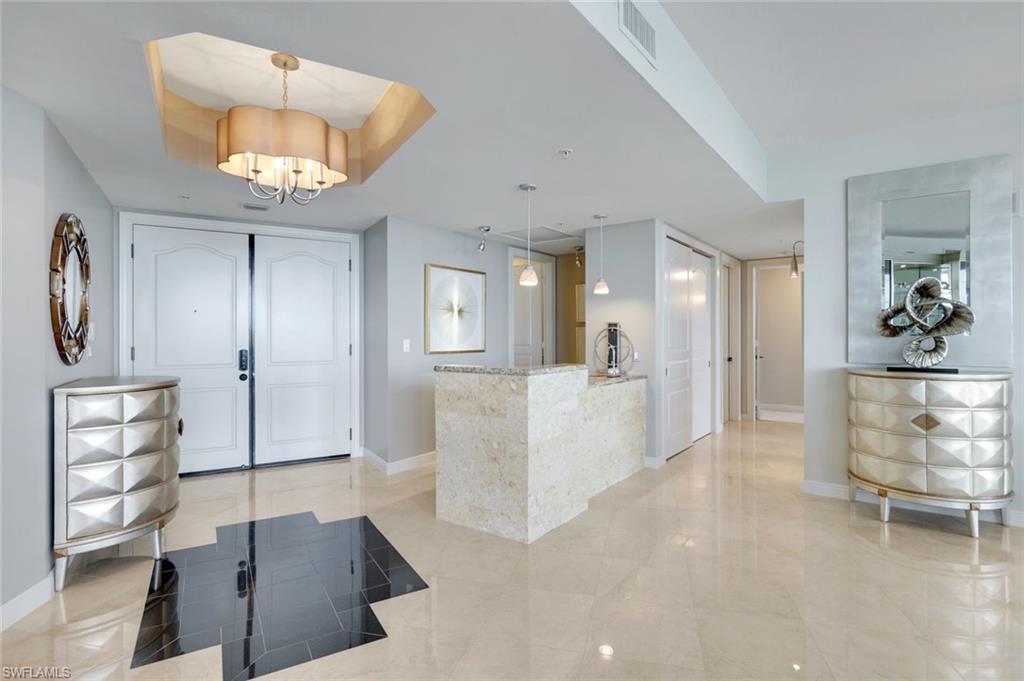 700 La Peninsula Boulevard, Unit 305 Naples, FL 34113 - Photo 8 of 39 wooden floor in a hall with an entryway and a chandelier