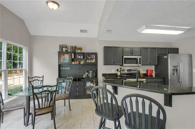 a kitchen with stainless steel appliances a dining table chairs and a refrigerator