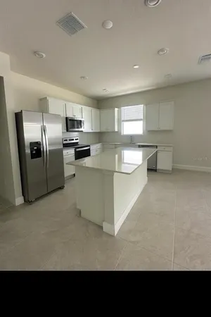 a living room with stainless steel appliances kitchen island granite countertop a refrigerator oven a sink a stove with white cabinets