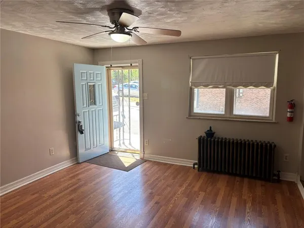 a view of an empty room with wooden floor and a window