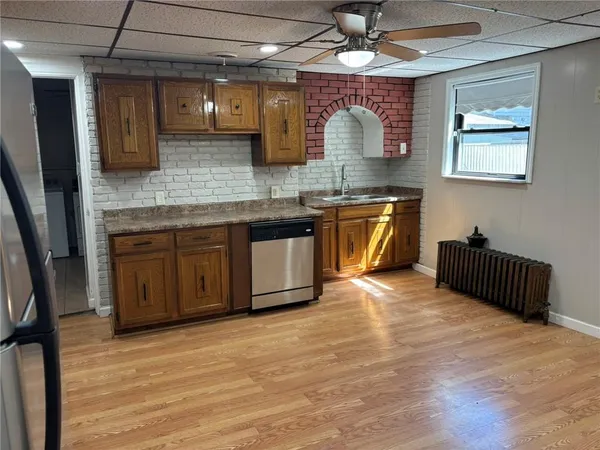 a kitchen with stainless steel appliances granite countertop a sink dishwasher a stove a microwave oven and a dining table with wooden floor