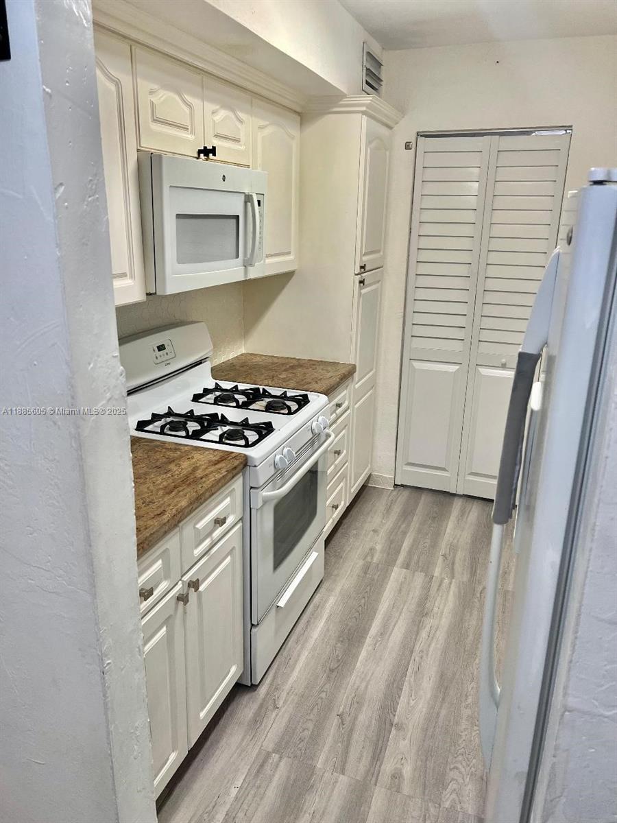1300 West 53rd Street, Unit 18 Hialeah, FL 33012 - Photo 7 of 16 a kitchen with white cabinets and white appliances