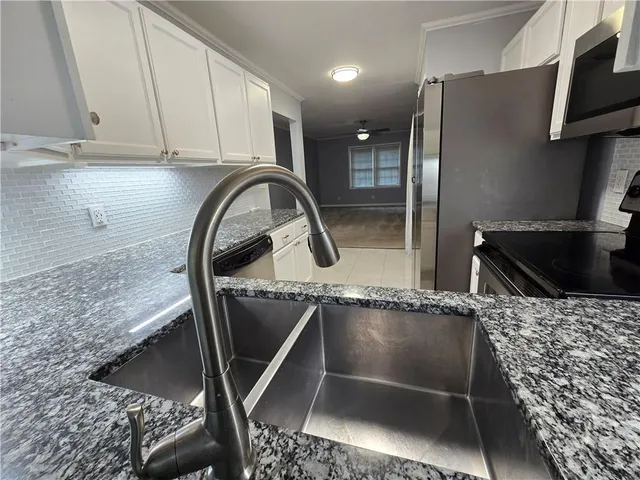 a kitchen with granite countertop white cabinets and stainless steel appliances