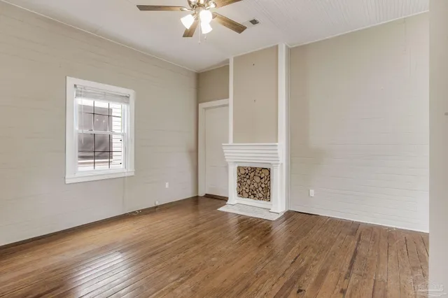 a view of an empty room with window and wooden floor