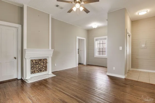 an empty room with wooden floor chandelier and windows