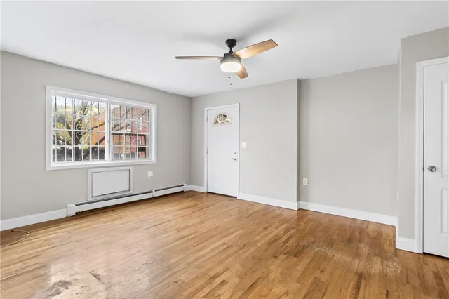 an empty room with wooden floor chandelier fan and windows