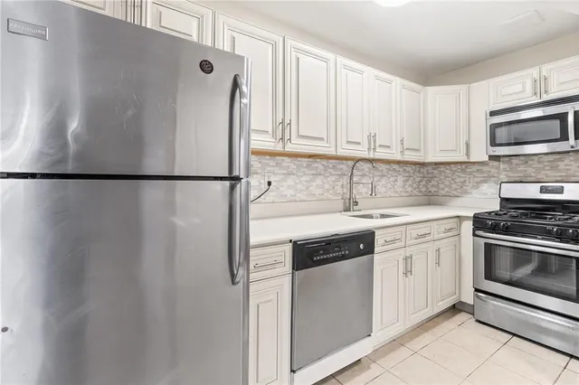 a white refrigerator freezer sitting inside of a kitchen with stainless steel appliances granite countertop cabinets and a refrigerator