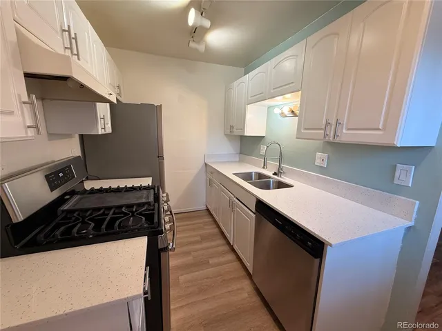 a kitchen with stainless steel appliances a sink a stove a refrigerator cabinets and a window