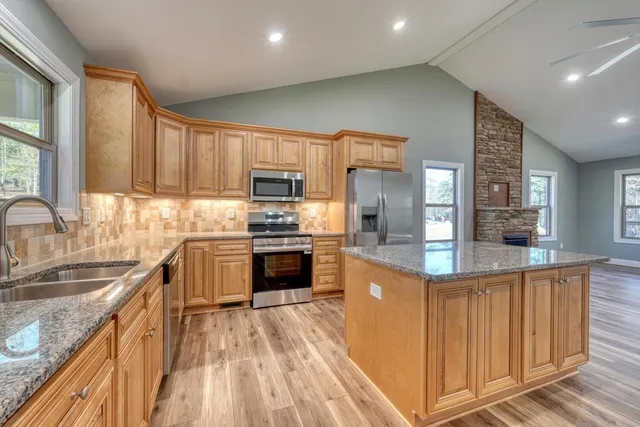 a kitchen with kitchen island granite countertop a sink stove and refrigerator
