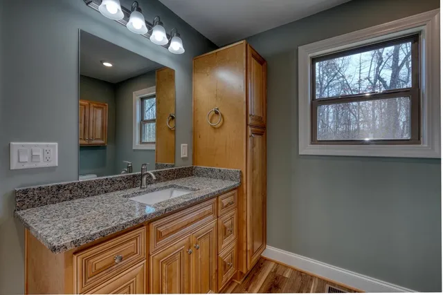 a bathroom with a granite countertop sink a large mirror and a shower