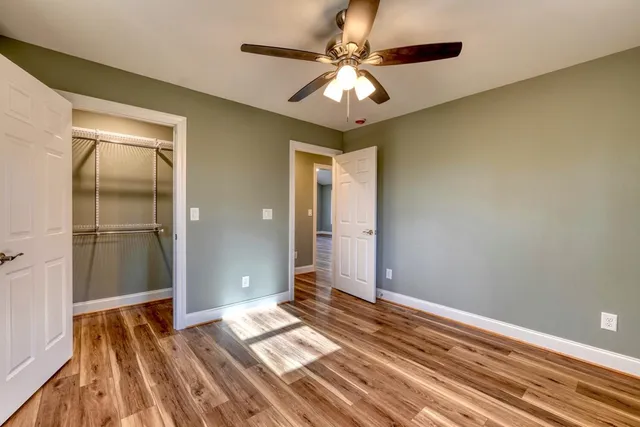 a view of a bedroom with wooden floor and a ceiling fan
