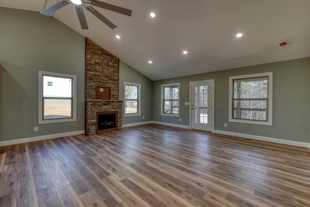 a view of an empty room with wooden floor fireplace and a window