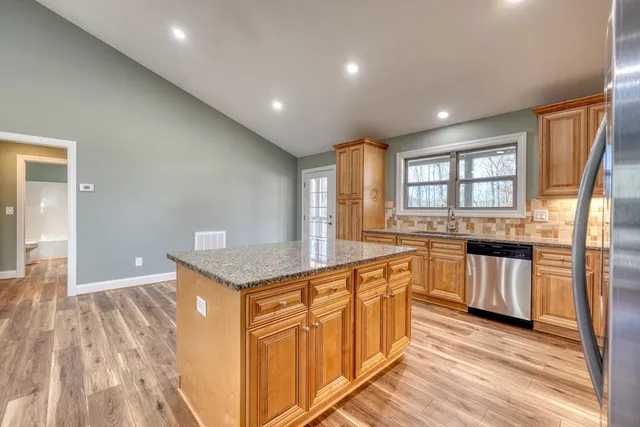 a kitchen with stainless steel appliances granite countertop a stove a sink and a refrigerator