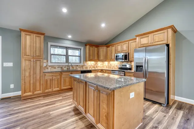 a kitchen with stainless steel appliances granite countertop a refrigerator a sink a stove and island