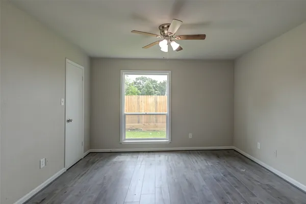 an empty room with wooden floor fireplace and windows