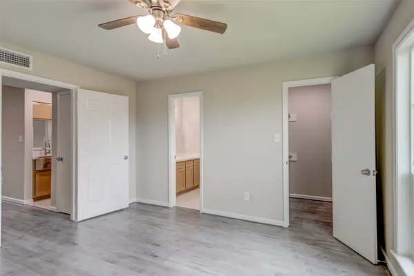 an empty room with wooden floor closet and windows