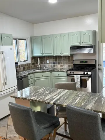 a kitchen with kitchen island granite countertop a sink a stove and refrigerator