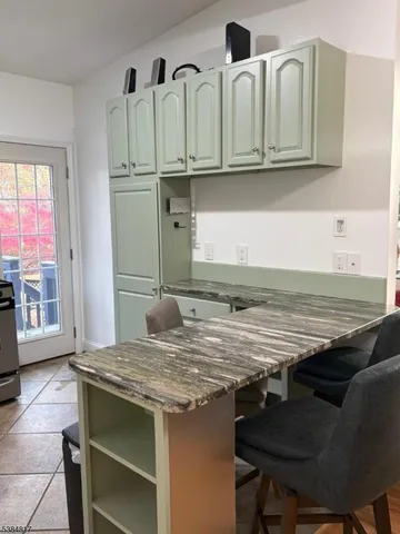 a view of kitchen with granite countertop white cabinets and a refrigerator
