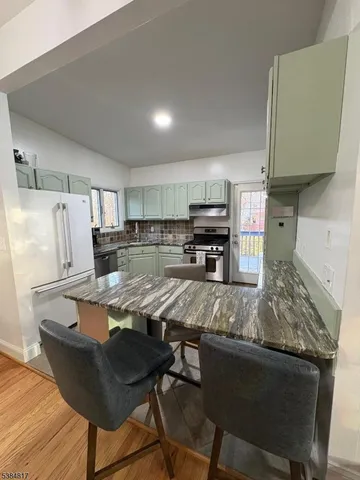 a kitchen with kitchen island granite countertop a sink cabinets and wooden floor