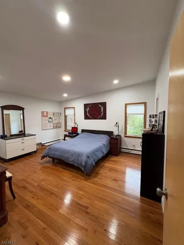 a spacious bedroom with a bed and wooden floor