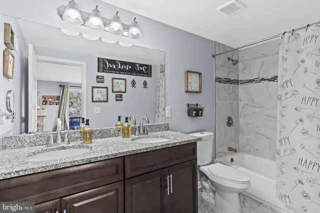 a bathroom with a granite countertop sink a toilet and shower