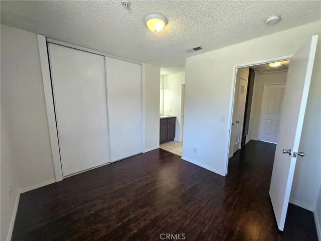 a view of an empty room with wooden floor and closet