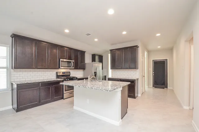 a large kitchen with stainless steel appliances kitchen island granite countertop a stove sink and cabinets