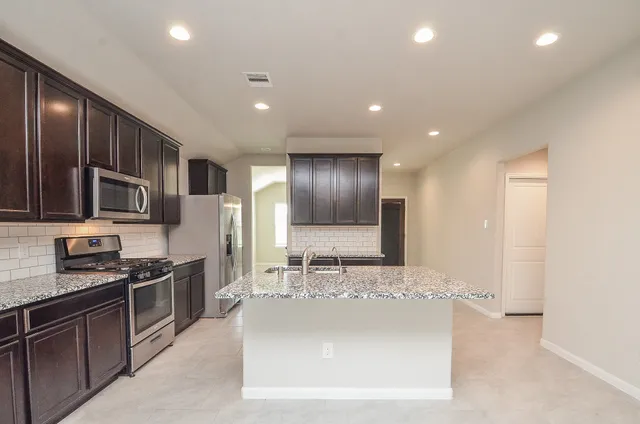 a large kitchen with stainless steel appliances kitchen island granite countertop a stove sink and cabinets
